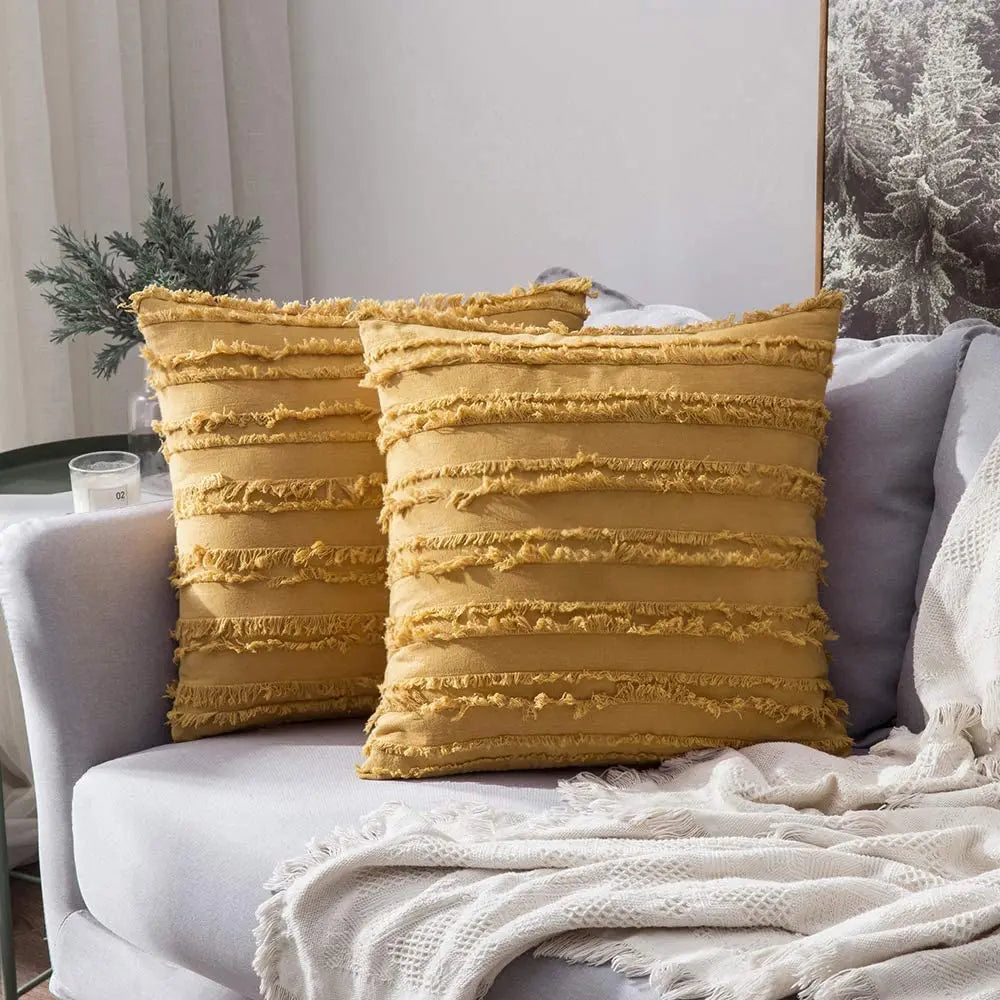 Two mustard yellow textured pillows on a gray sofa with a white blanket.