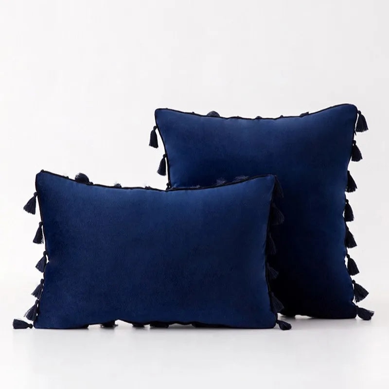 Two navy blue pillows with tassels on a white background