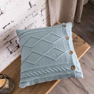 Light blue cable knit pillow cover with geometric diamond pattern and buttons