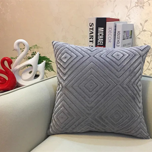 Gray textured pillow on a light-colored sofa with decorative items in the background.