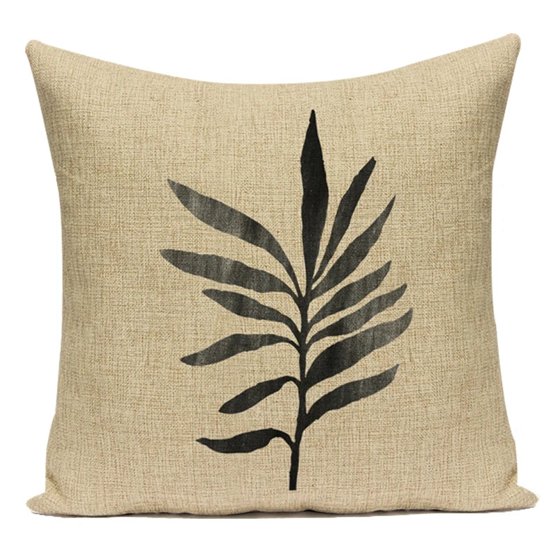 Beige pillow with black leaf design on a white background