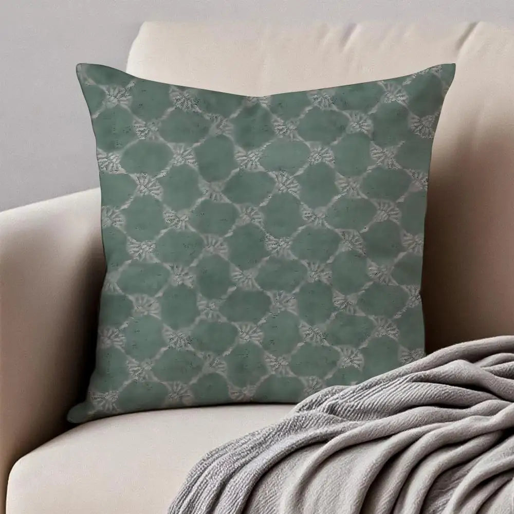 Green patterned pillow on a beige sofa with a gray blanket.