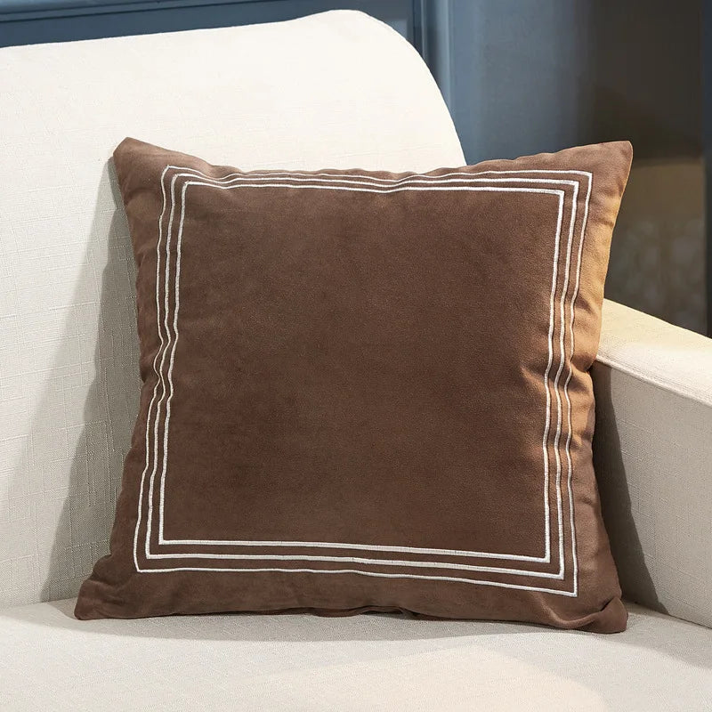 Brown pillow with white trim on a white couch