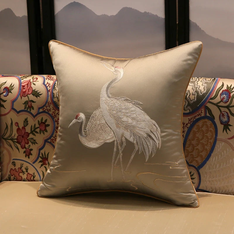 Decorative pillow with embroidered crane design on a neutral background