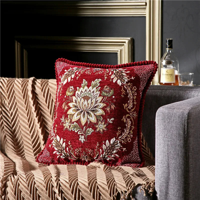 Decorative red pillow with floral pattern on a couch in a living room setting.