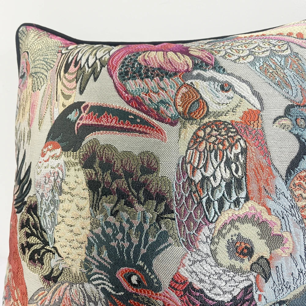 Decorative pillow with intricate bird and floral pattern on a neutral background