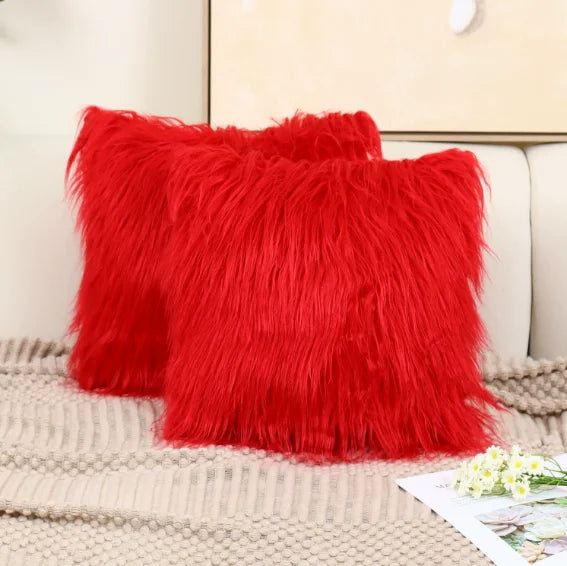 Two red fluffy pillows on a beige sofa with a neutral background