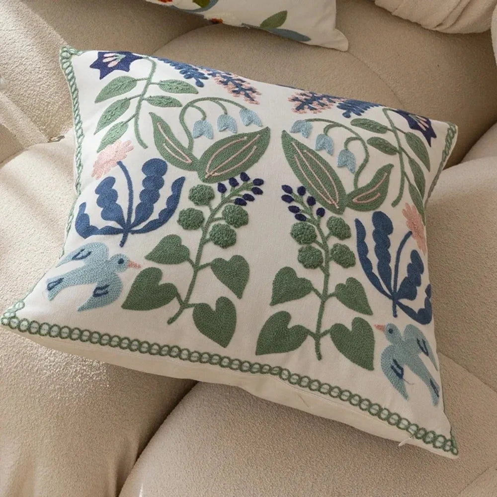Decorative pillow with floral and bird pattern on a beige sofa