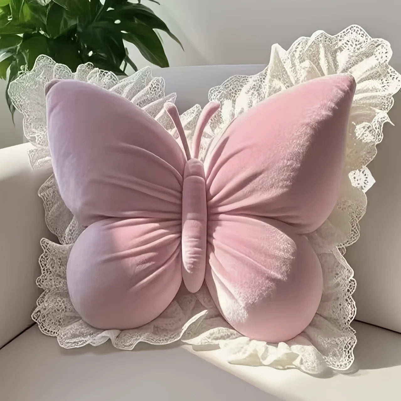 Pink butterfly-shaped pillow on a white surface with lace trim