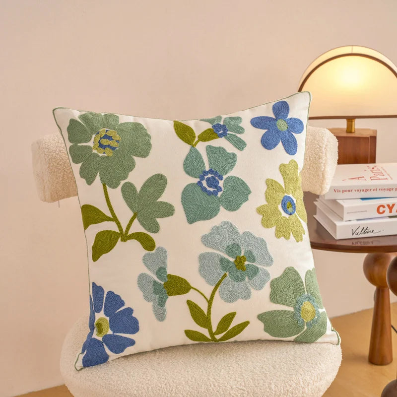 Floral-patterned pillow on a chair with a lamp and books in the background