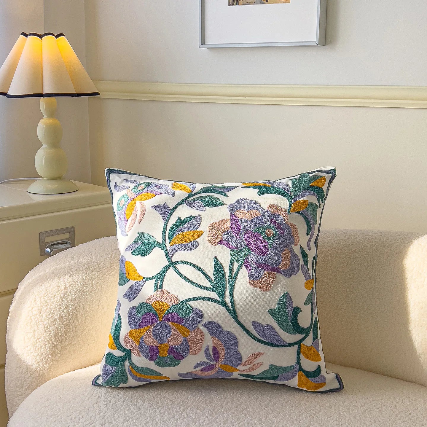 Decorative pillow with floral pattern on a couch next to a lamp.