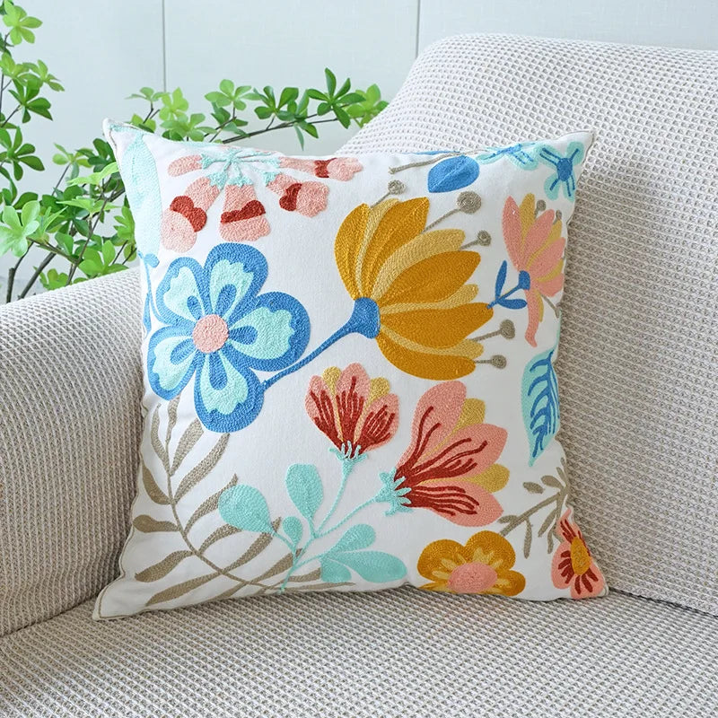Floral-patterned pillow on a couch with a light blue wall and green plants in the background