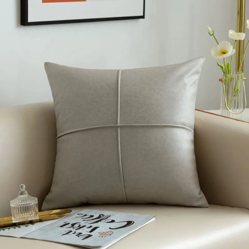 Gray pillow on a beige sofa with a vase of flowers in the background