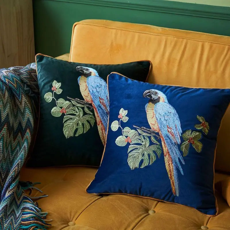 Decorative pillows with parrot designs on a yellow couch.