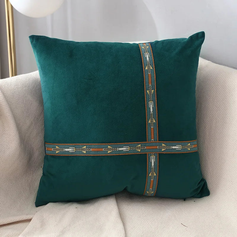 Green pillow with decorative band on a beige sofa