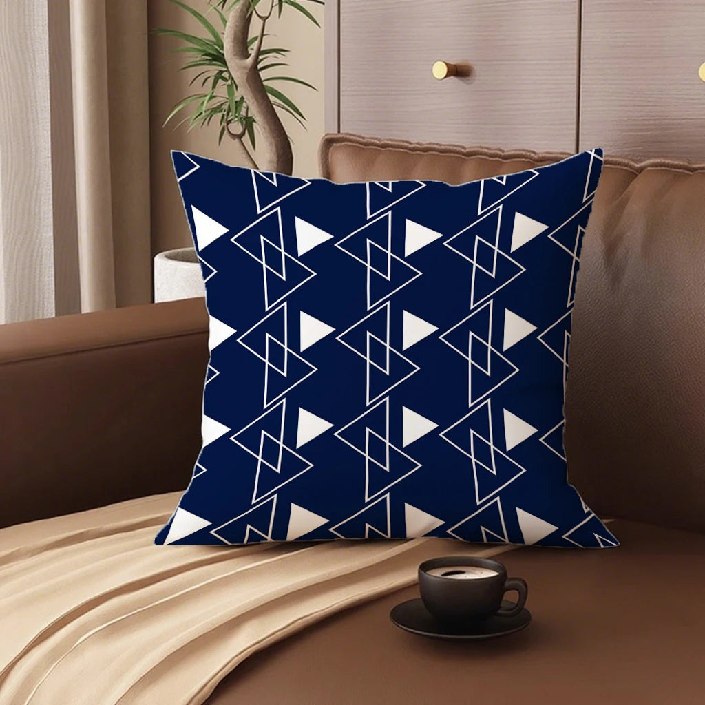 Blue and white geometric patterned pillow on a brown couch with a cup of coffee.
