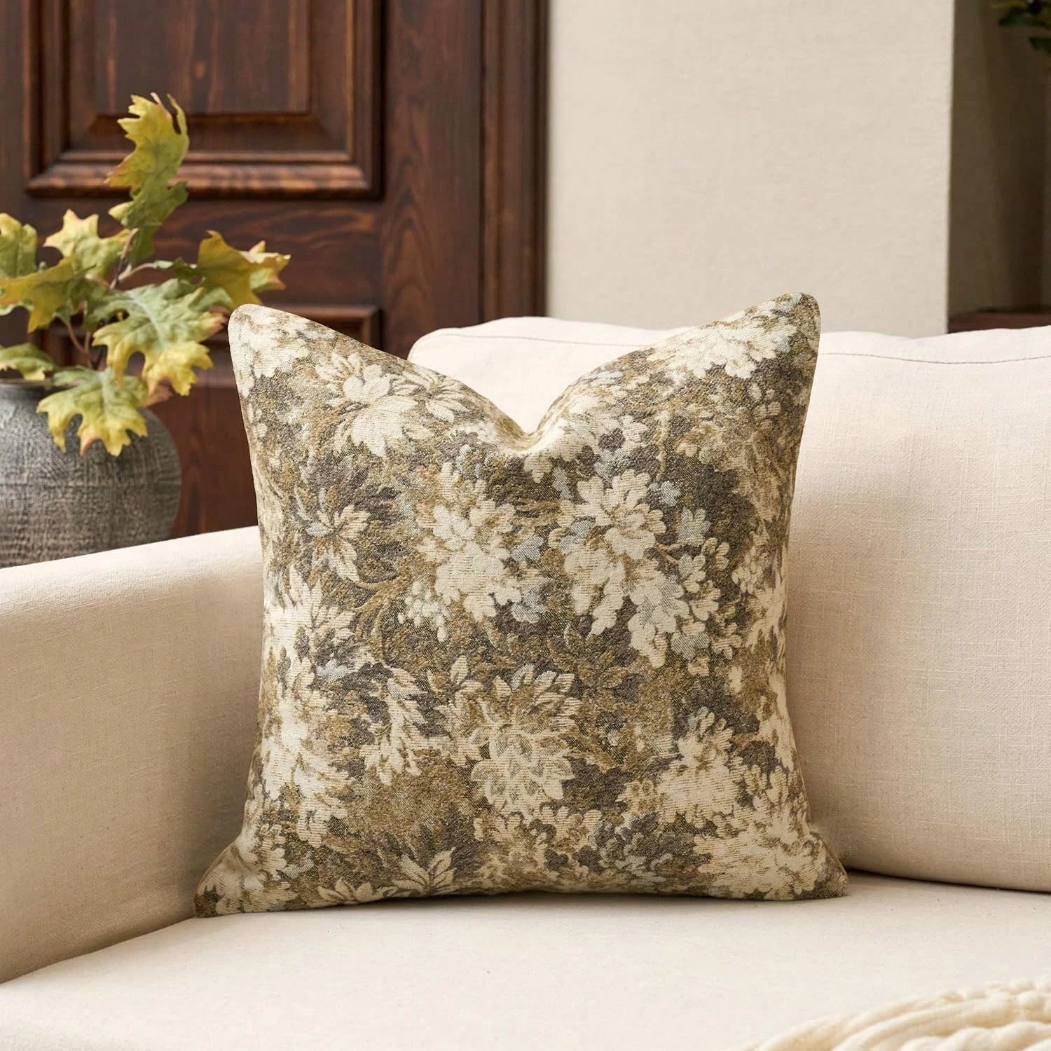 Floral-patterned pillow on a beige sofa with a plant in the background
