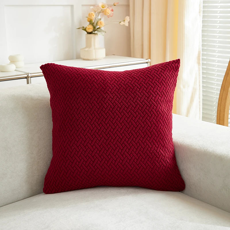 Red textured pillow on a white couch with a blurred background