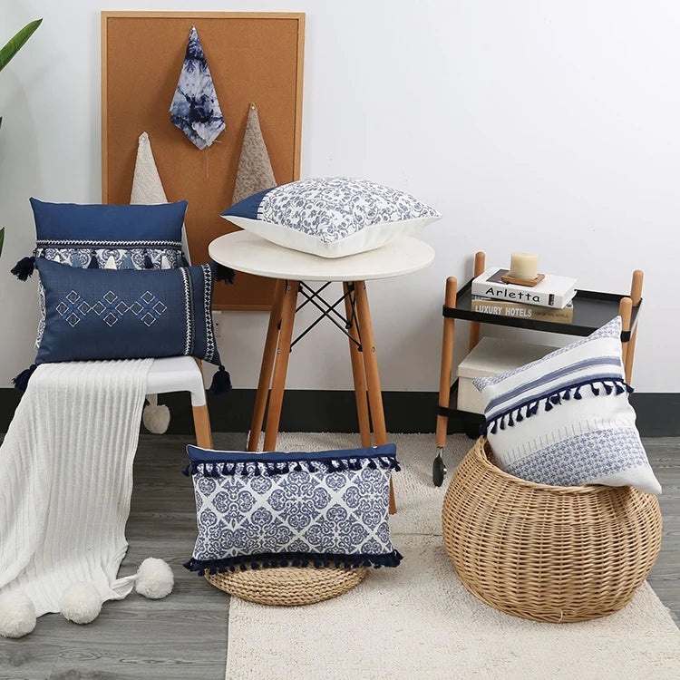 Decorative pillows with blue and white patterns on a chair and stool in a room setting.