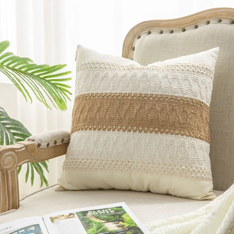 Decorative pillow with brown and beige stripes on a couch with a plant in the background