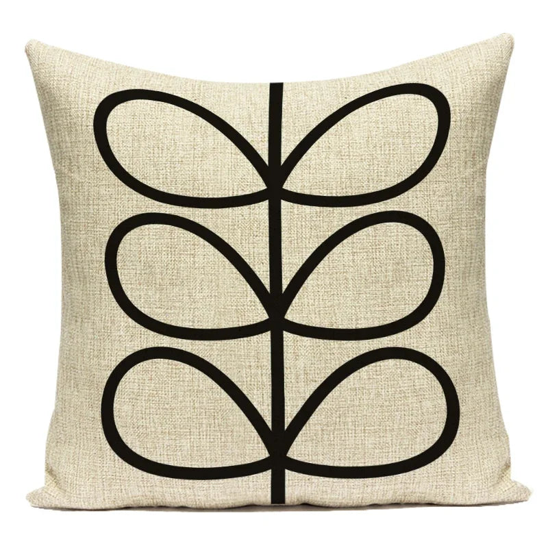 Beige pillow with black abstract leaf design on a white background