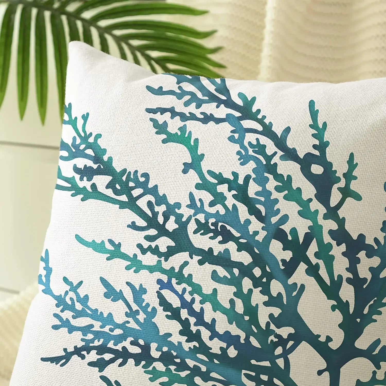 Decorative pillow with teal coral pattern on a beige background