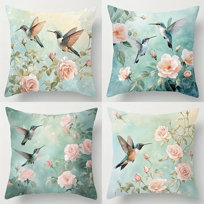 Four decorative pillows with hummingbird and floral design on a light blue background