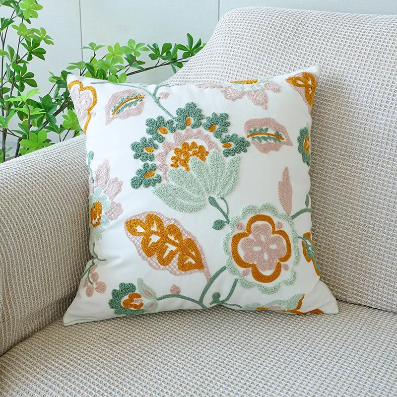 Floral patterned pillow on a beige couch with green plants in the background