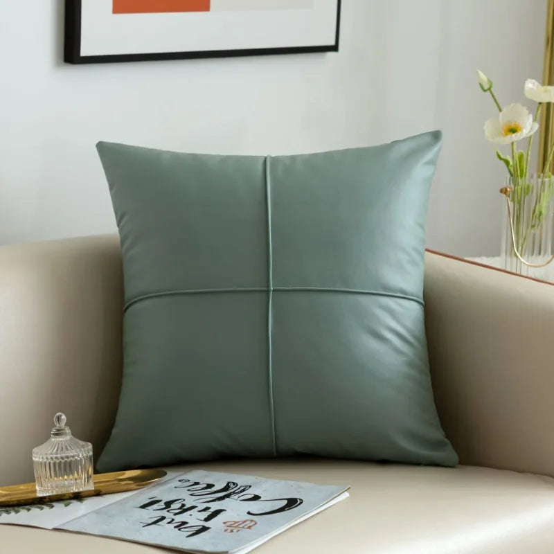 Green pillow on a beige sofa with a decorative tray and flowers in the background