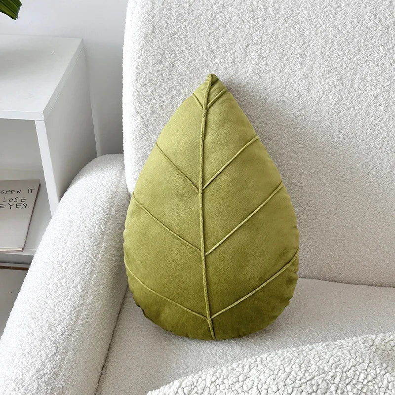 Green leaf-shaped pillow on a white sofa