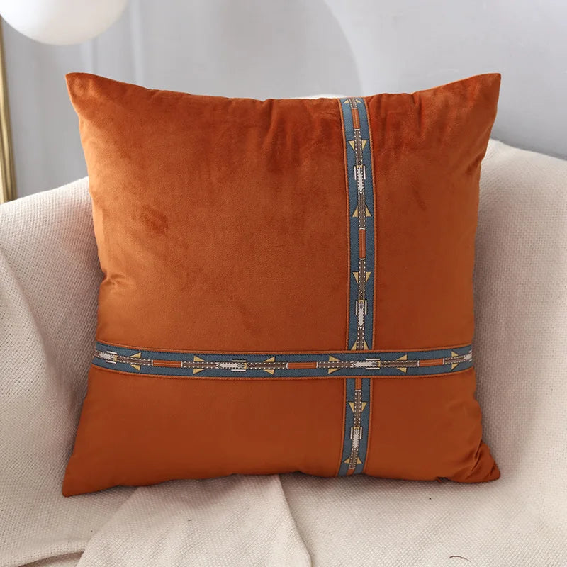 Orange pillow with decorative band on a beige armchair