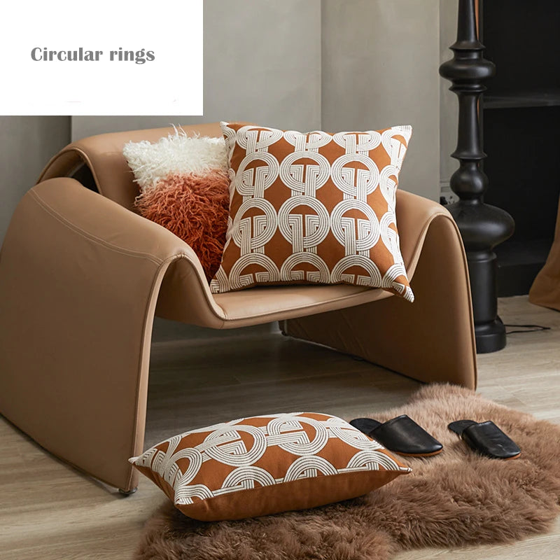 Brown armchair with patterned cushions on a wooden floor.