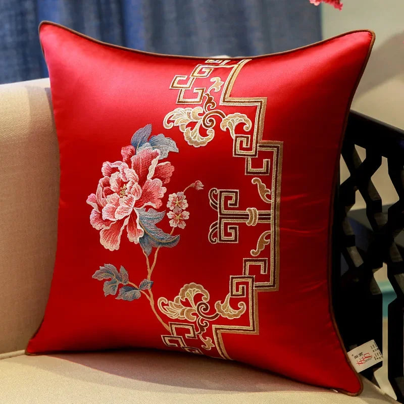 Red decorative pillow with floral embroidery on a beige couch.