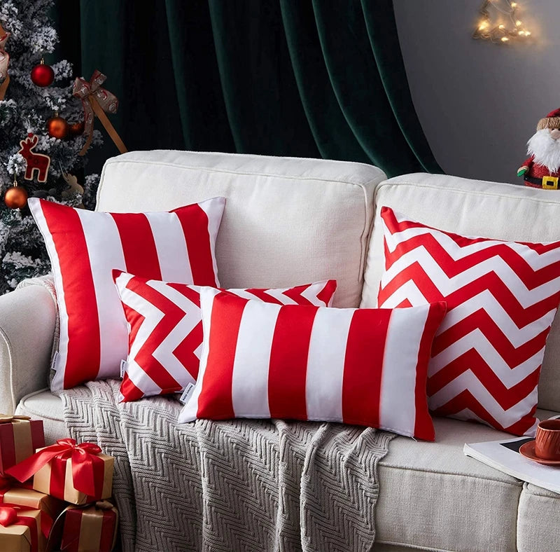 Red and white striped pillows on a beige sofa with a Christmas tree in the background.
