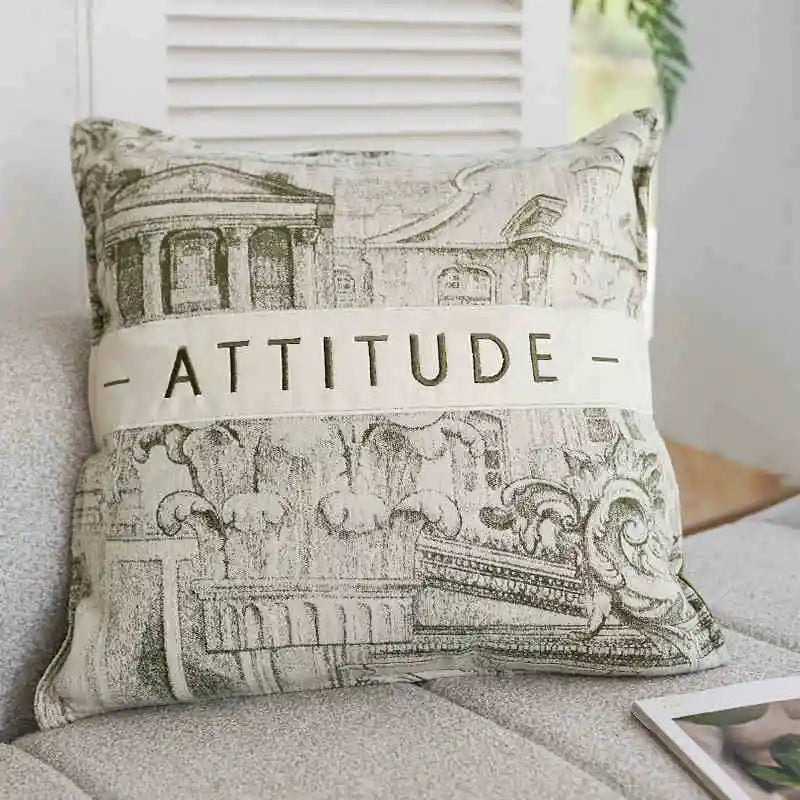 Decorative pillow with architectural design and 'ATTITUDE' text on a couch.