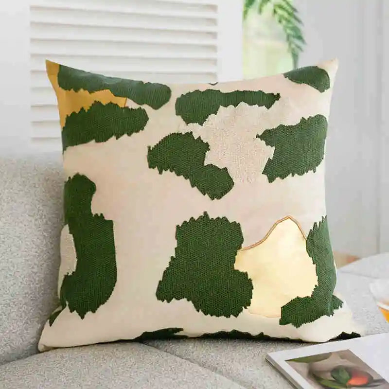 Decorative pillow with green leaf pattern on a neutral background