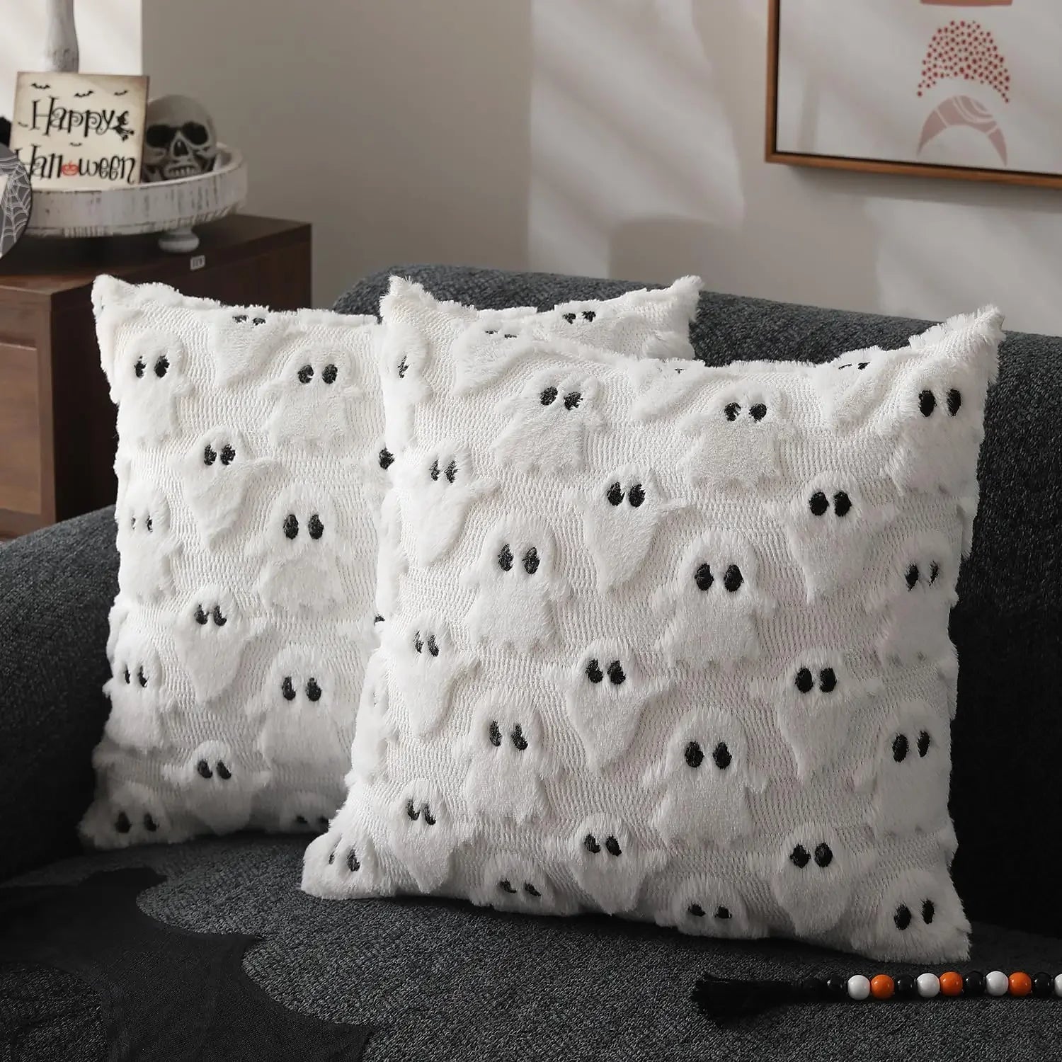 White decorative pillows with black patterns on a gray couch.