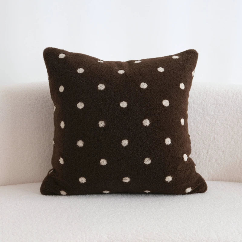 Brown pillow with white polka dots on a white couch