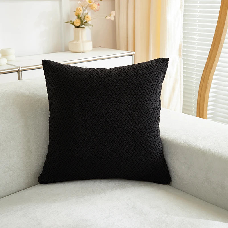 Black textured pillow on a white sofa with a blurred background