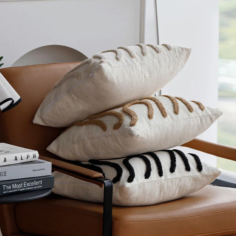 Stack of decorative pillows on a brown leather chair with books underneath.