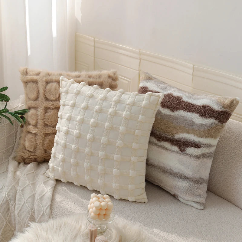 Three decorative pillows on a sofa with a neutral color palette.