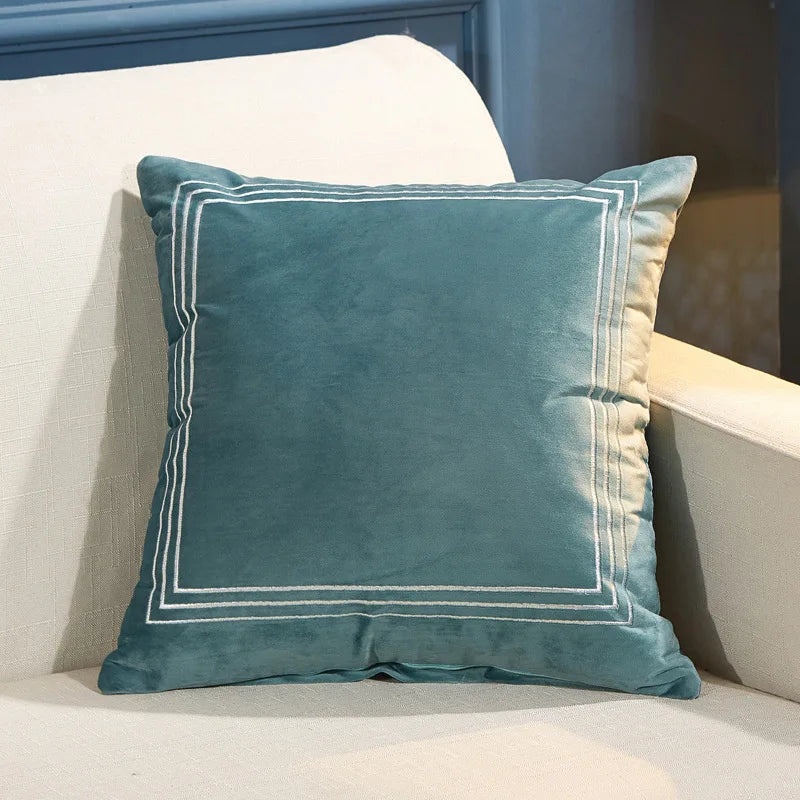 Teal pillow with white trim on a beige couch