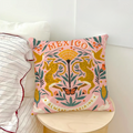 Pink throw pillow featuring Mexican folk art illustrations and wildlife.