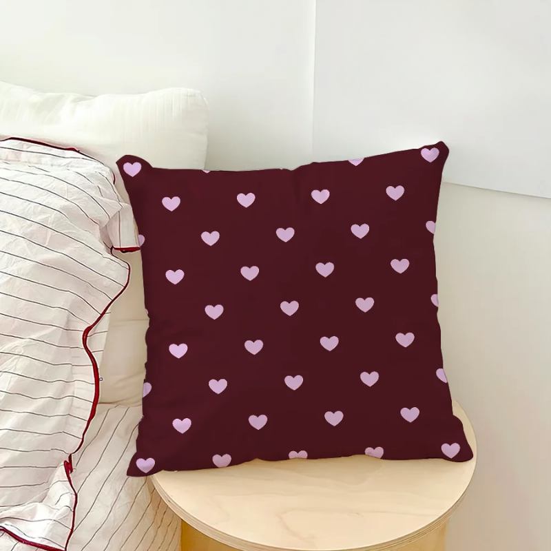 Maroon pillow with pink heart pattern on a white couch