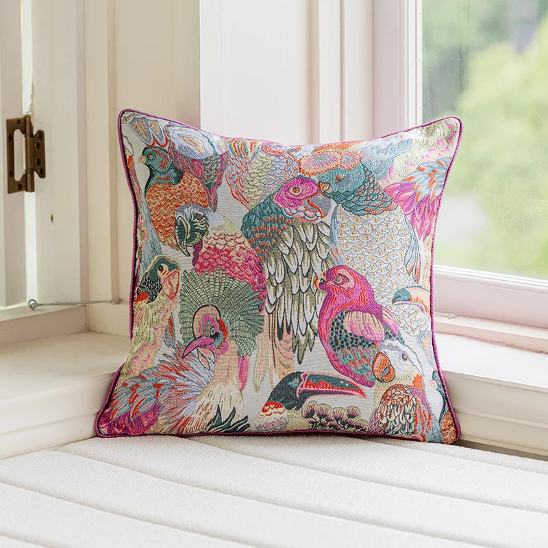 Colorful bird-patterned pillow on a white cushion by a window