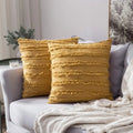 Two mustard yellow textured pillows on a gray sofa with a white blanket.