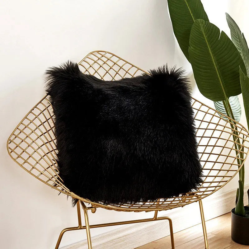 Black fluffy pillow on a gold wire chair with a plant in the background