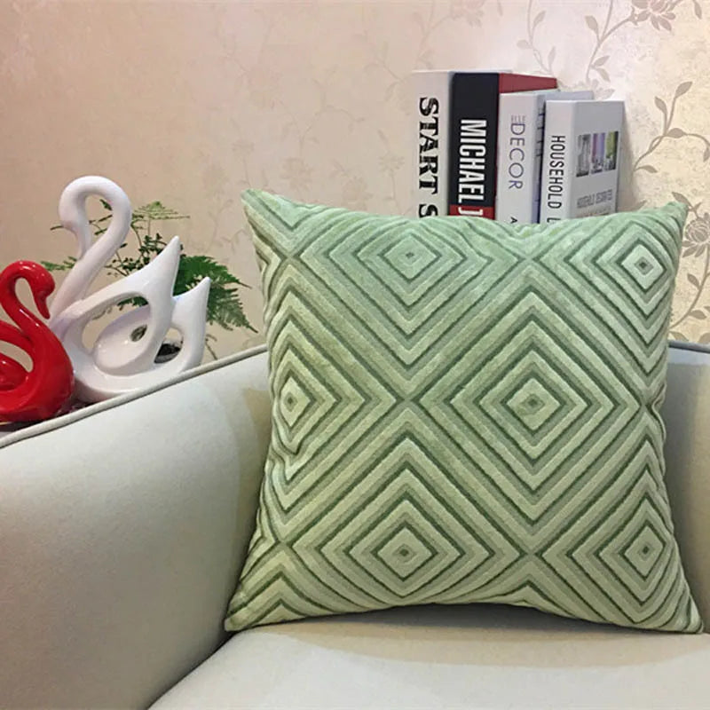 Green patterned pillow on a couch with decorative items in the background