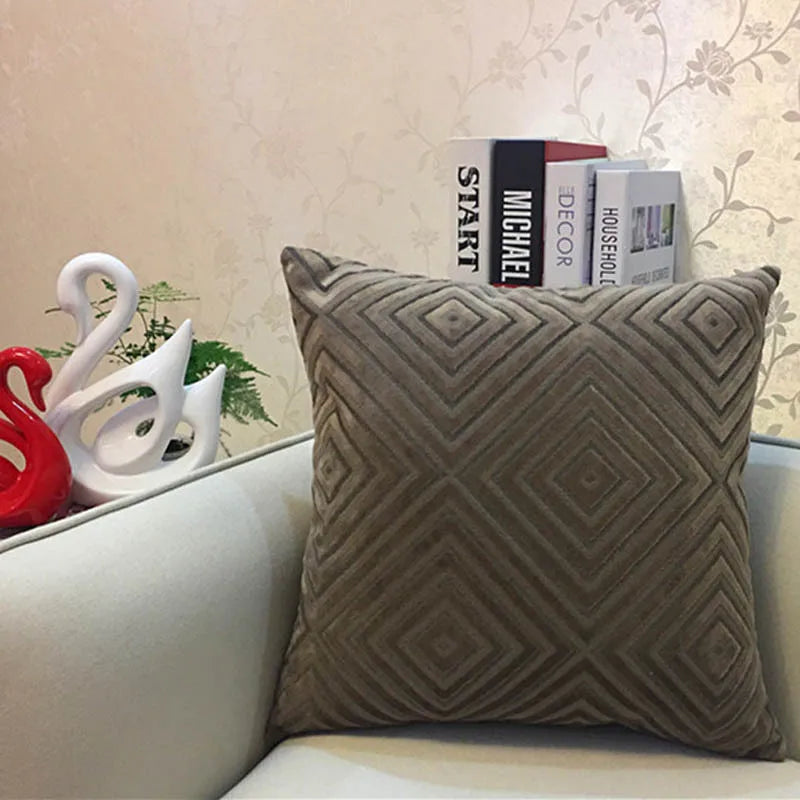 Decorative pillow with geometric pattern on a couch against a floral wallpaper background