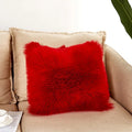 Red fluffy pillow on a beige couch with a white wall background